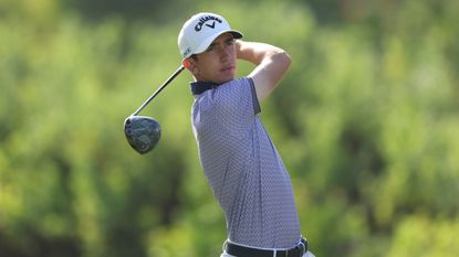 Golfer swinging iron club on course