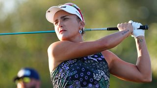 Woman swings golf club on course